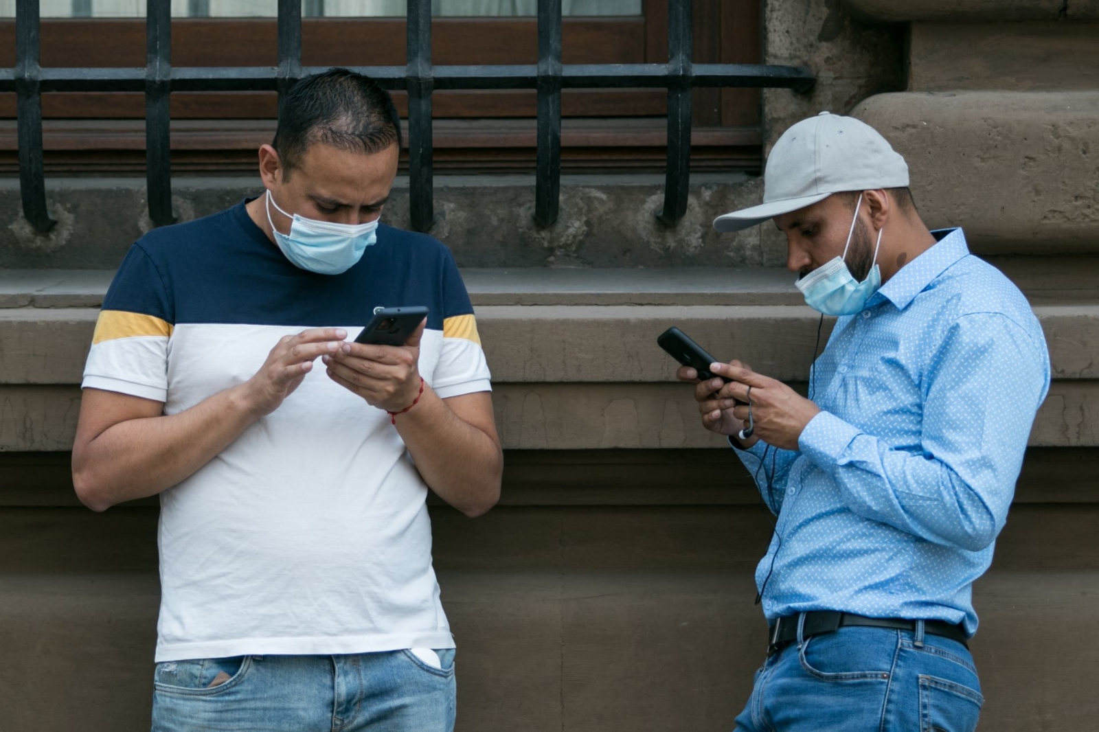 Dos hombres revisan sus teléfonos celulares