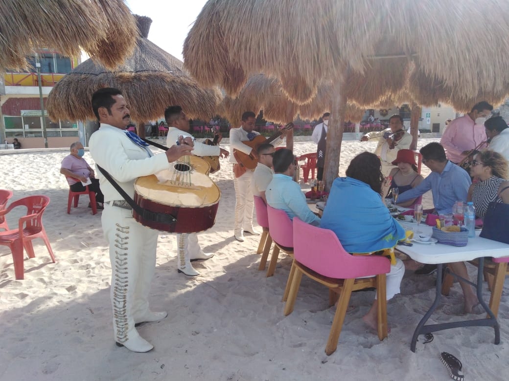 Mariachis le cantan a turistas en la playa de Progreso