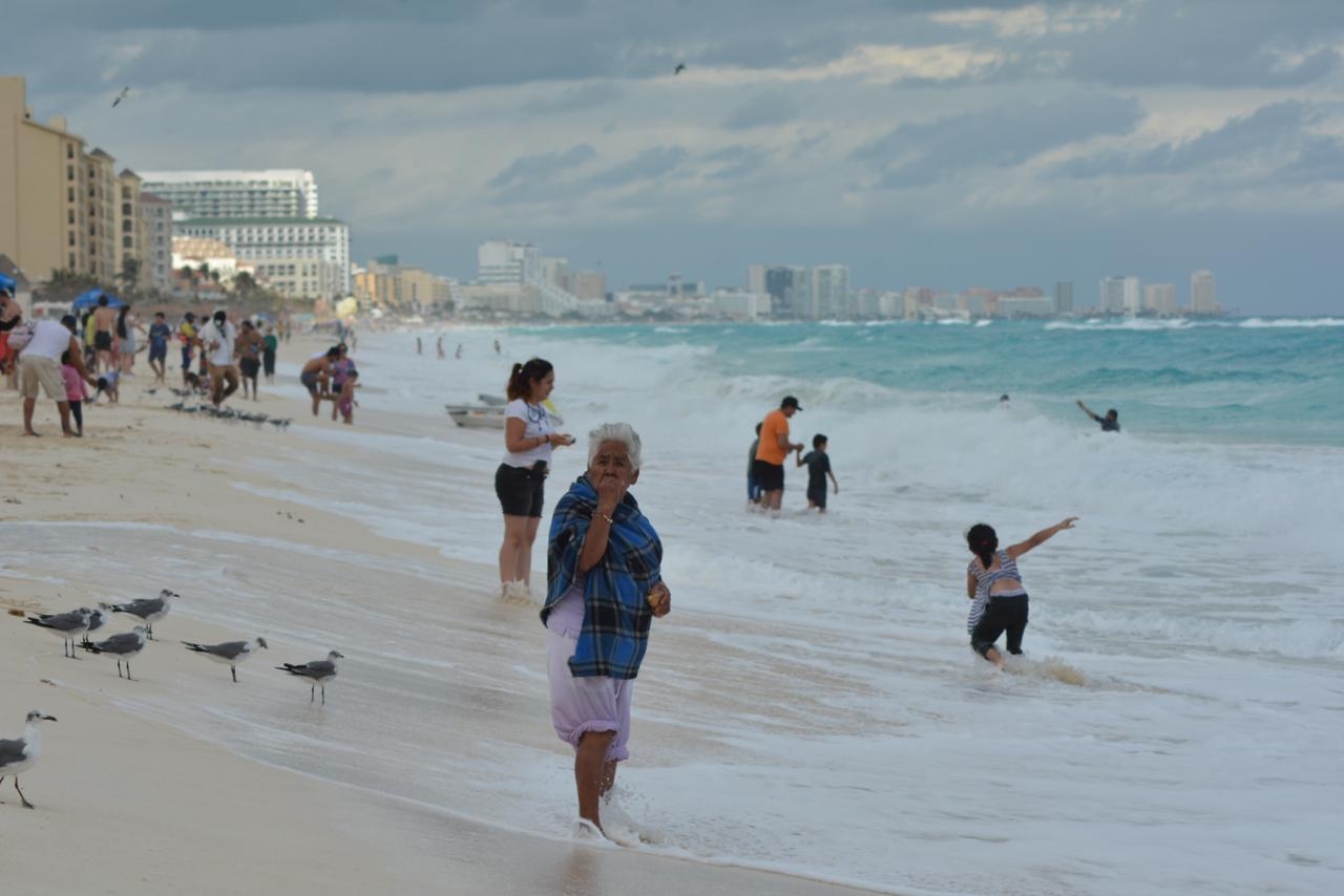 Nublado o con sol, turistas abarrotan playas de Cancún