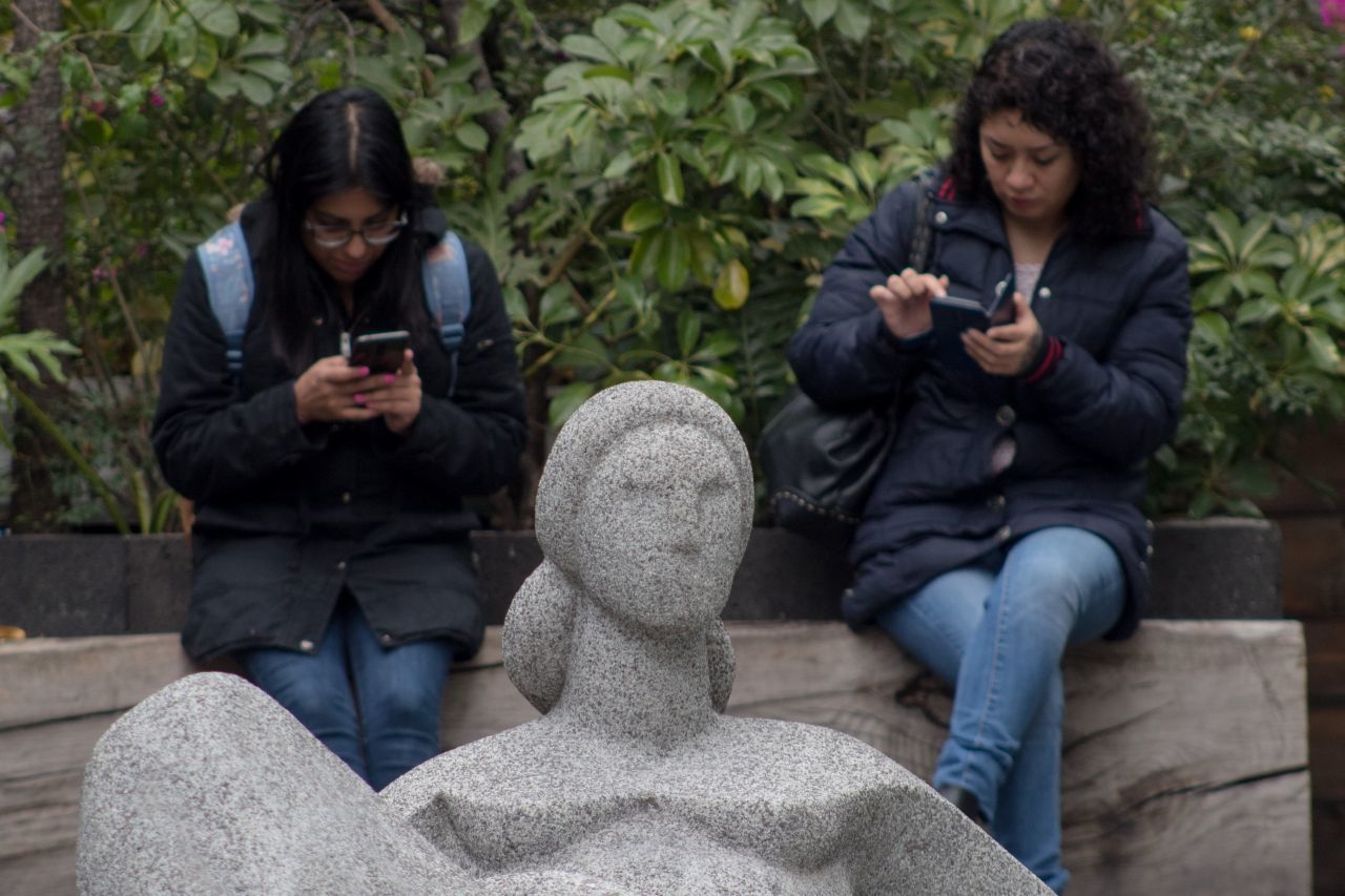 Dos jóvenes en sus teléfonos celulares