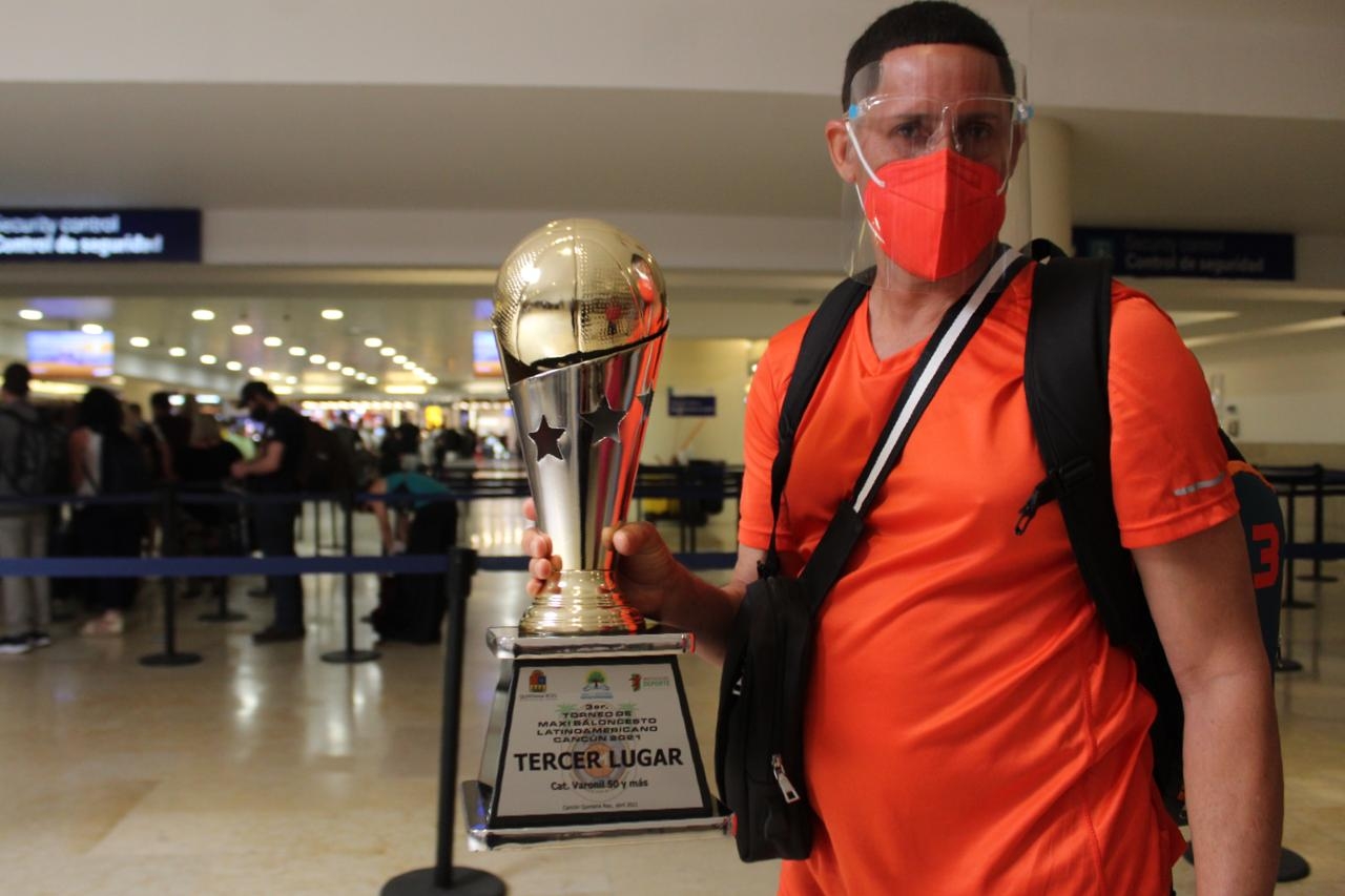 Basquetbolista pasea por el aeropuerto con trofeo ganado en torneo de Cancún
