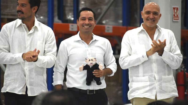 Mauricio Vila recibe peluche del Dr. Simi en la inauguración del nuevo Centro de Farmacias Similares